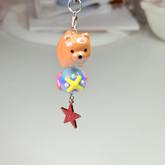 Keychain with a dog-shaped bead and colorful ball, hanging from a red star charm.