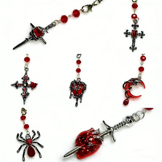 Alternative Y2K aesthetic phone accessories with silver dagger through red heart and gothic cross charms.
