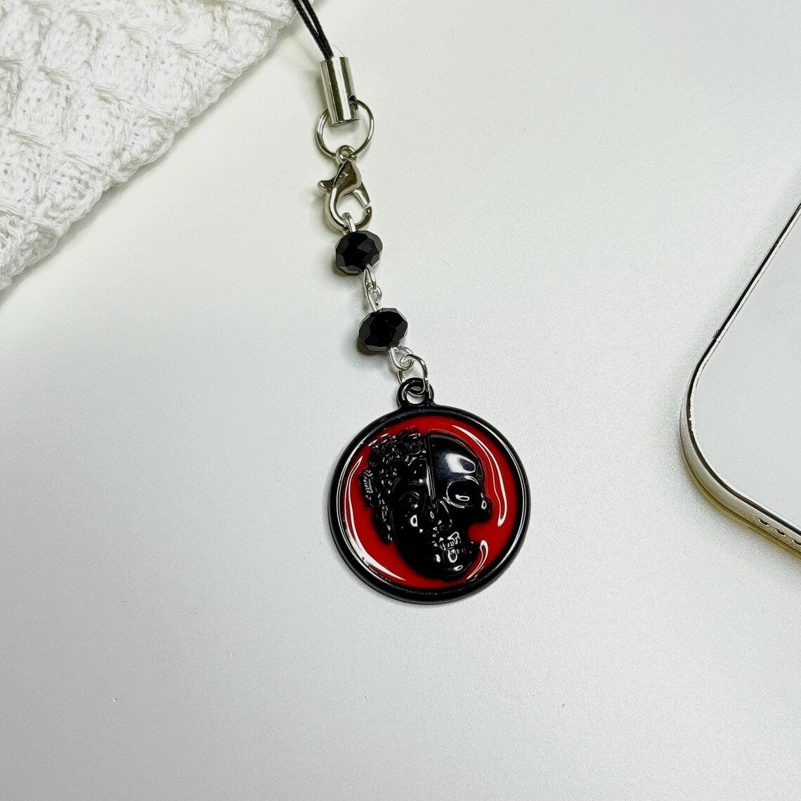 Phone charm with red and black design on a white surface